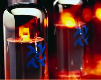 Glowing vacuum tubes in close-up, orange filaments behind glass printed with a blue logo
